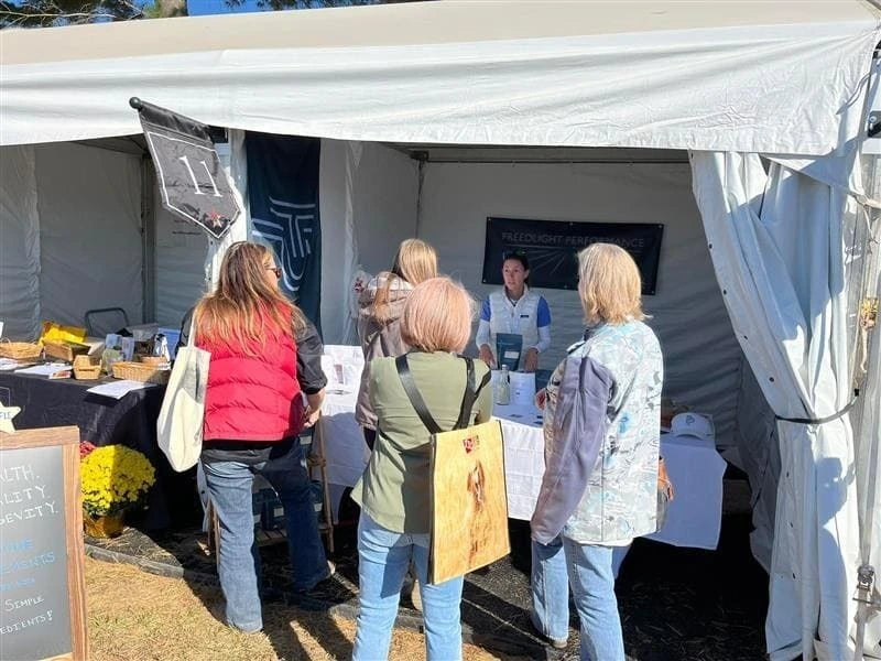 Group of people gathered under a tent at an outdoor event.